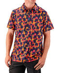 Men’s Palm Drip Dusk golf polo by Pins & Aces featuring navy palm tree silhouettes over a vibrant orange, pink, and purple tropical sunset print with an athletic fit.