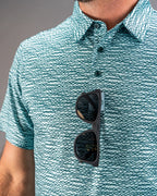 Men’s Squiggle Teal golf polo by Pins & Aces featuring an all-over aqua and teal abstract wavy squiggle pattern with short sleeves and an athletic performance fit.