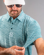 Men’s Squiggle Teal golf polo by Pins & Aces featuring an all-over aqua and teal abstract wavy squiggle pattern with short sleeves and an athletic performance fit.