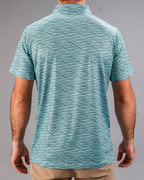 Men’s Squiggle Teal golf polo by Pins & Aces featuring an all-over aqua and teal abstract wavy squiggle pattern with short sleeves and an athletic performance fit.