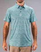 Men’s Squiggle Teal golf polo by Pins & Aces featuring an all-over aqua and teal abstract wavy squiggle pattern with short sleeves and an athletic performance fit.