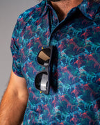 Men’s Swordfish Skelly golf polo by Pins & Aces featuring a blue, teal, and red ocean-inspired swordfish pattern with short sleeves and an athletic performance fit.