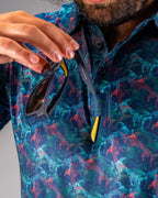 Men’s Swordfish Skelly golf polo by Pins & Aces featuring a blue, teal, and red ocean-inspired swordfish pattern with short sleeves and an athletic performance fit.