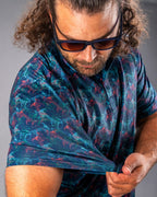 Men’s Swordfish Skelly golf polo by Pins & Aces featuring a blue, teal, and red ocean-inspired swordfish pattern with short sleeves and an athletic performance fit.