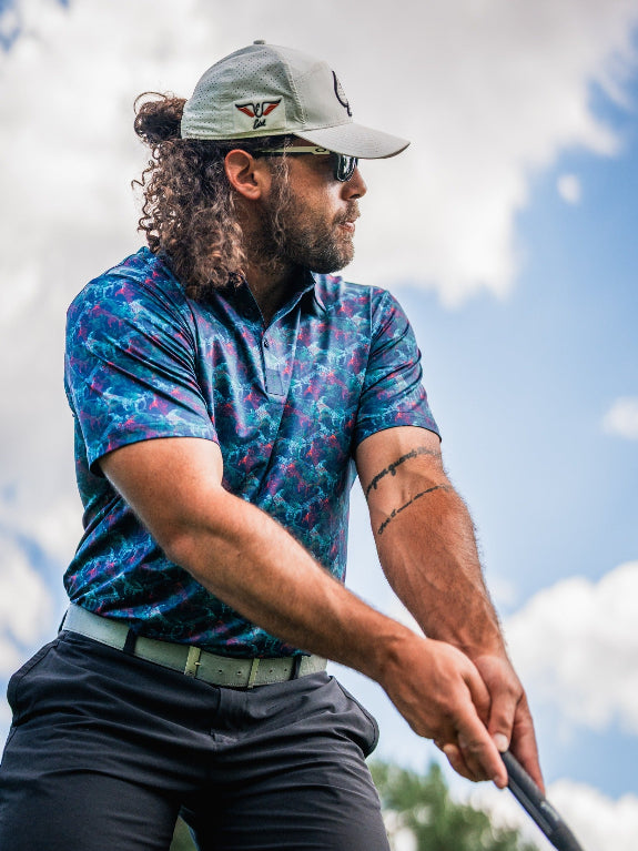 Men’s Swordfish Skelly golf polo by Pins & Aces featuring a blue, teal, and red ocean-inspired swordfish pattern with short sleeves and an athletic performance fit.