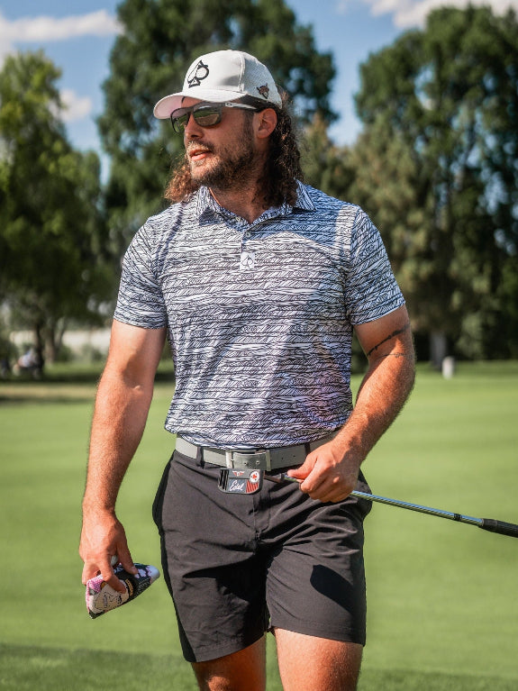 Men’s Fragment Black golf polo by Pins & Aces featuring an all-over black, white, and gray abstract line pattern with short sleeves and an athletic performance fit.