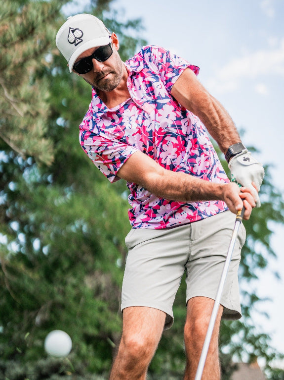 Men’s Brushed Flowers golf polo by Pins & Aces featuring a bold pink, blush, white, blue, and navy floral print with short sleeves and an athletic performance fit.