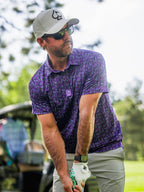Men’s Doodle Guy Purple golf polo by Pins & Aces featuring an all-over purple, violet, blue, and green doodle-inspired pattern with short sleeves and an athletic performance fit.