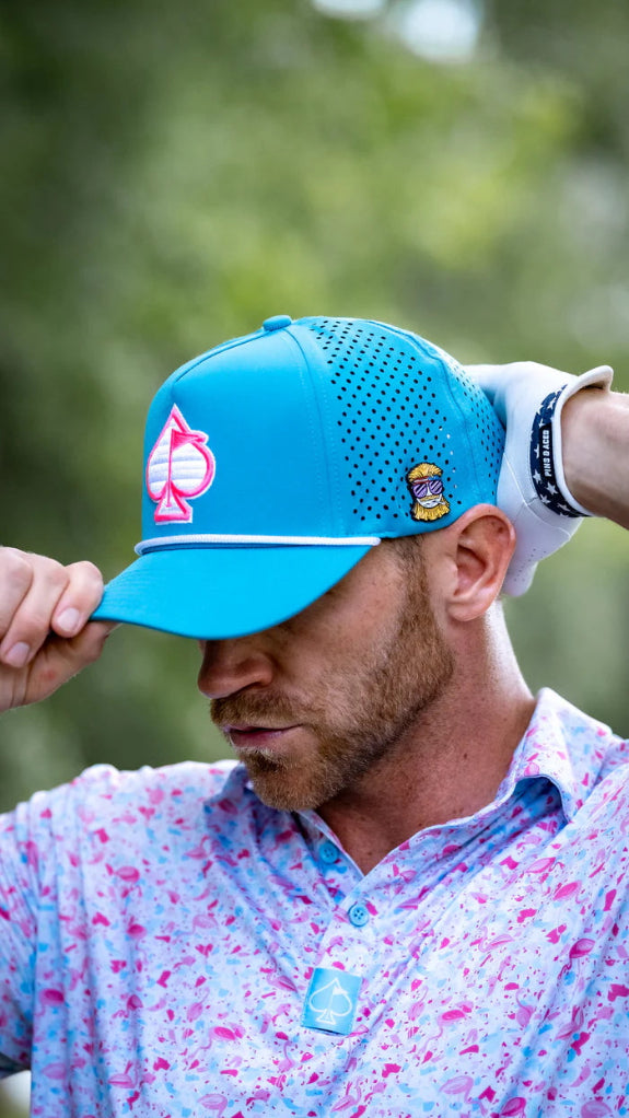 Baby blue perforated rope golf hat by Pins & Aces featuring a pink and white embroidered Fairway Wave Spade logo, white rope accent, perforated panels, and curved bill.