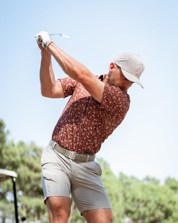Men’s Autumn Bloom golf polo by Pins & Aces featuring a rust-colored all-over cream floral print, short sleeves, blade collar, and athletic performance fit.