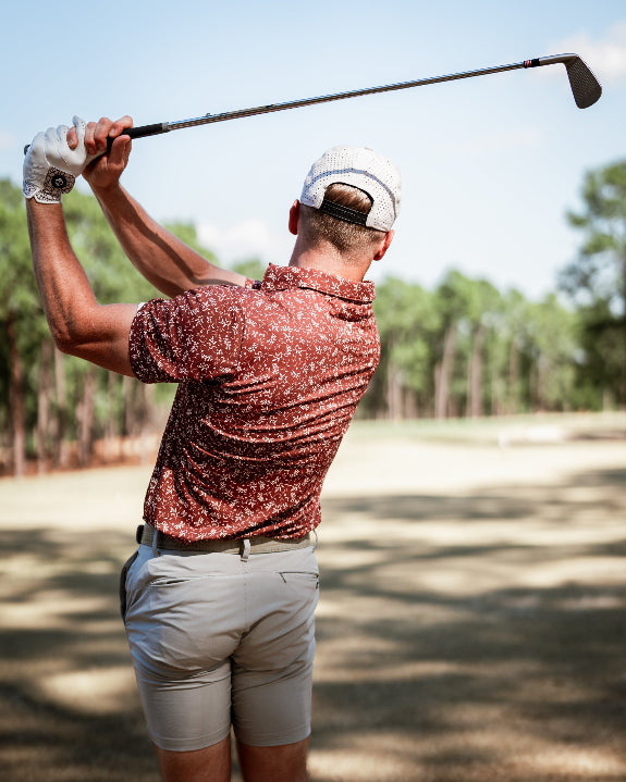 Men’s Autumn Bloom golf polo by Pins & Aces featuring a rust-colored all-over cream floral print, short sleeves, blade collar, and athletic performance fit.