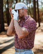 Men’s Autumn Bloom golf polo by Pins & Aces featuring a rust-colored all-over cream floral print, short sleeves, blade collar, and athletic performance fit.