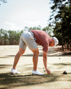 Men’s Autumn Bloom golf polo by Pins & Aces featuring a rust-colored all-over cream floral print, short sleeves, blade collar, and athletic performance fit.