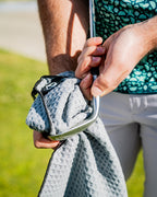 White Pins & Aces magnetic golf towel featuring durable waffle-knit fabric, a strong built-in magnet, center slit, and carabiner for attaching to a golf bag.
