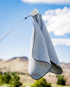 White Pins & Aces magnetic golf towel featuring durable waffle-knit fabric, a strong built-in magnet, center slit, and carabiner for attaching to a golf bag.