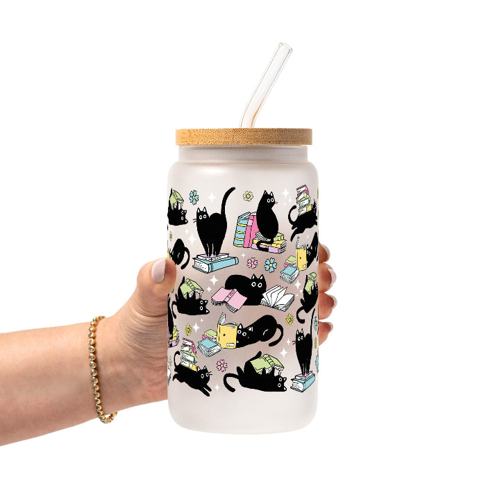 Black Cats on Books drinkware design featuring whimsical black cats lounging on colorful stacks of books with pastel flowers and bookish details.
