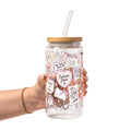Clear glass cup with bamboo lid and straw featuring a pink pastel bookish collage with books, flowers, reading glasses, hearts and feminine reader-themed sayings.