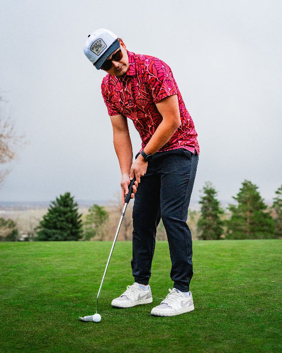 Men’s Garden Party Crimson Bloom golf polo by Pins & Aces featuring an oversized crimson, red, pink, and burgundy floral print with short sleeves and an athletic performance fit.