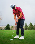 Men’s Garden Party Crimson Bloom golf polo by Pins & Aces featuring an oversized crimson, red, pink, and burgundy floral print with short sleeves and an athletic performance fit.