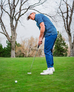 Men’s Rising Tides golf polo by Pins & Aces featuring a repeating blue and navy wave-inspired pattern, short sleeves, and an athletic performance fit.
