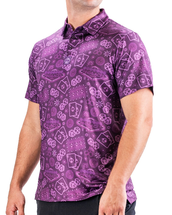 Men’s purple casino golf polo by Pins & Aces featuring an all-over pattern of playing cards, dice, poker chips, slot machines, and Las Vegas-inspired graphics.