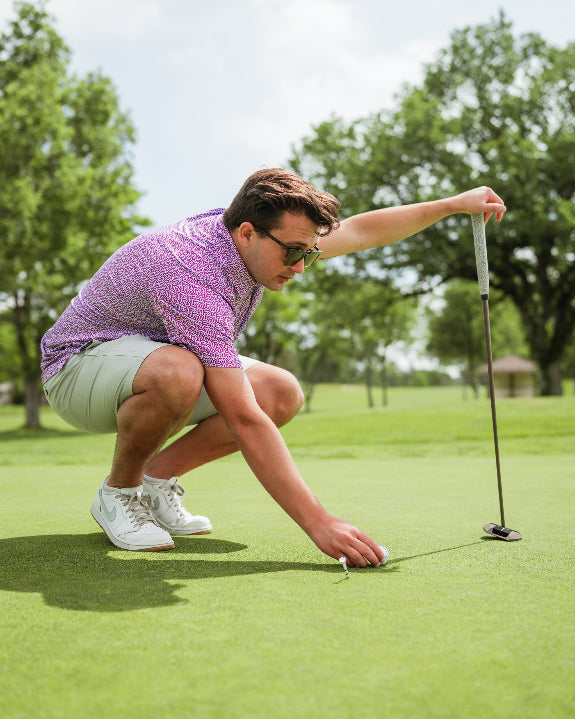 Men’s Sugar Circuit golf polo by Pins & Aces featuring a vibrant pink, purple, and blue geometric all-over pattern with short sleeves and an athletic performance fit.