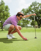 Men’s Sugar Circuit golf polo by Pins & Aces featuring a vibrant pink, purple, and blue geometric all-over pattern with short sleeves and an athletic performance fit.