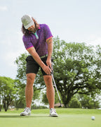 Men’s Eighties Arcade golf polo by Pins & Aces featuring a purple retro geometric print with pink and teal accents, short sleeves, and an athletic performance fit.