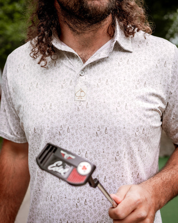 Men’s Drinking Buddies golf polo by Pins & Aces featuring a subtle drinking-inspired all-over print on a cream short-sleeve performance polo with an athletic fit.