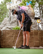 Men’s Moon Burn golf polo by Pins & Aces featuring an abstract purple, blue, and black cosmic-inspired pattern with short sleeves and an athletic performance fit.