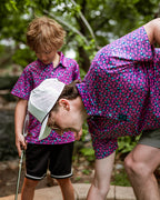 Men’s Full Bloom golf polo by Pins & Aces featuring an all-over bright pink floral pattern on a navy background with short sleeves and an athletic performance fit.