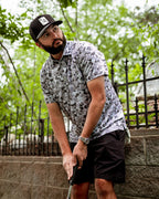 Men’s Arctic Ops golf polo by Pins & Aces featuring an all-over gray, silver, and black camouflage print with short sleeves, collared neckline, and athletic performance fit.