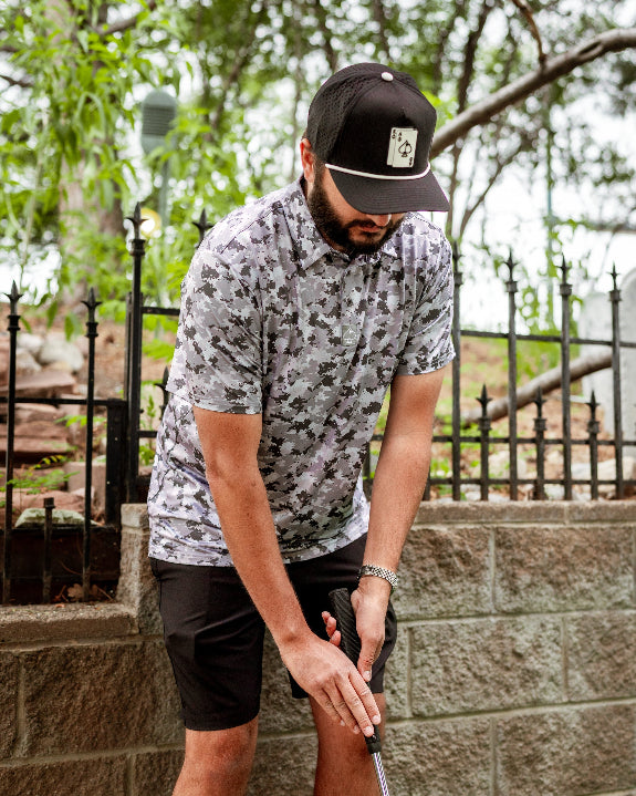 Men’s Arctic Ops golf polo by Pins & Aces featuring an all-over gray, silver, and black camouflage print with short sleeves, collared neckline, and athletic performance fit.