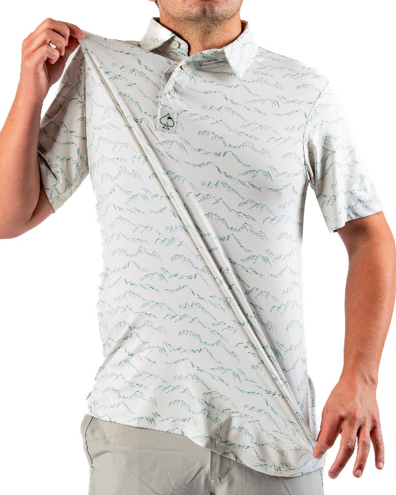 Men’s Altitude Adjustment golf polo by Pins & Aces featuring an off-white base with a subtle blue-green mountain range print, short sleeves, and athletic performance fit.