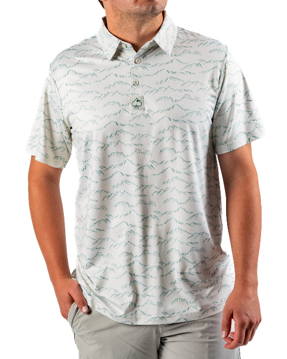 Men’s Altitude Adjustment golf polo by Pins & Aces featuring an off-white base with a subtle blue-green mountain range print, short sleeves, and athletic performance fit.
