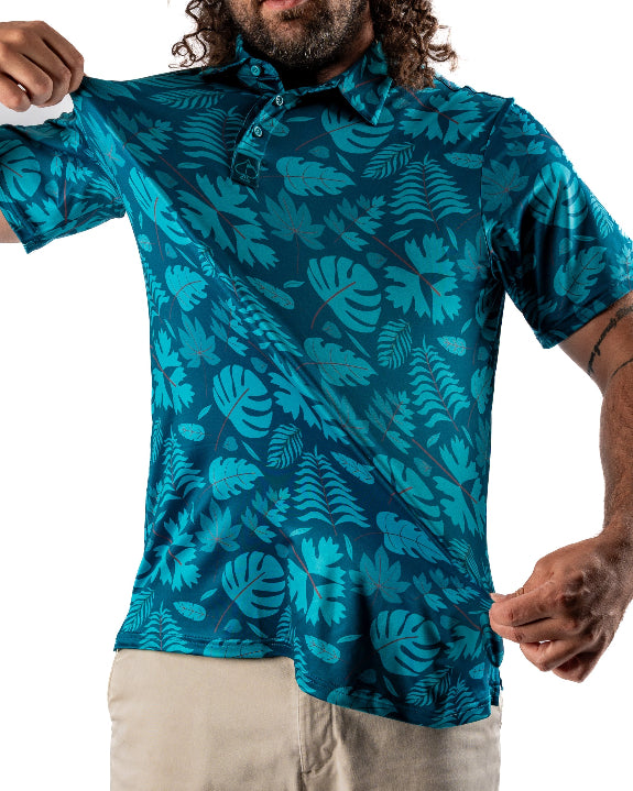Men’s Cabana Nights golf polo by Pins & Aces featuring a blue and teal tropical leaf print, short sleeves, and athletic performance fit.