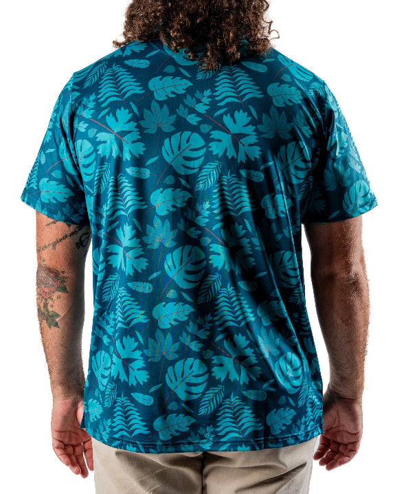 Men’s Cabana Nights golf polo by Pins & Aces featuring a blue and teal tropical leaf print, short sleeves, and athletic performance fit.