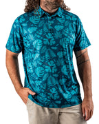 Men’s Cabana Nights golf polo by Pins & Aces featuring a blue and teal tropical leaf print, short sleeves, and athletic performance fit.