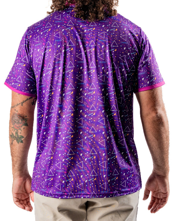 Men’s Eighties Arcade golf polo by Pins & Aces featuring a purple retro geometric print with pink and teal accents, short sleeves, and an athletic performance fit.