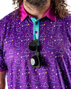 Men’s Eighties Arcade golf polo by Pins & Aces featuring a purple retro geometric print with pink and teal accents, short sleeves, and an athletic performance fit.