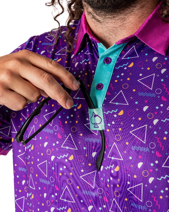 Men’s Eighties Arcade golf polo by Pins & Aces featuring a purple retro geometric print with pink and teal accents, short sleeves, and an athletic performance fit.