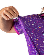 Men’s Eighties Arcade golf polo by Pins & Aces featuring a purple retro geometric print with pink and teal accents, short sleeves, and an athletic performance fit.