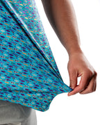 Men’s Fish & Drips golf polo by Pins & Aces featuring a bright aqua blue all-over fish print with colorful fishing-inspired details, short sleeves, and an athletic performance fit.