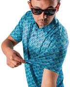 Men’s Fish & Drips golf polo by Pins & Aces featuring a bright aqua blue all-over fish print with colorful fishing-inspired details, short sleeves, and an athletic performance fit.