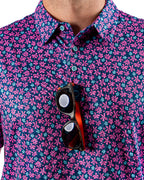 Men’s Full Bloom golf polo by Pins & Aces featuring an all-over bright pink floral pattern on a navy background with short sleeves and an athletic performance fit.