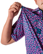 Men’s Full Bloom golf polo by Pins & Aces featuring an all-over bright pink floral pattern on a navy background with short sleeves and an athletic performance fit.