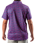 Men’s Full Bloom golf polo by Pins & Aces featuring an all-over bright pink floral pattern on a navy background with short sleeves and an athletic performance fit.