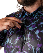 Men’s Moon Burn golf polo by Pins & Aces featuring an abstract purple, blue, and black cosmic-inspired pattern with short sleeves and an athletic performance fit.