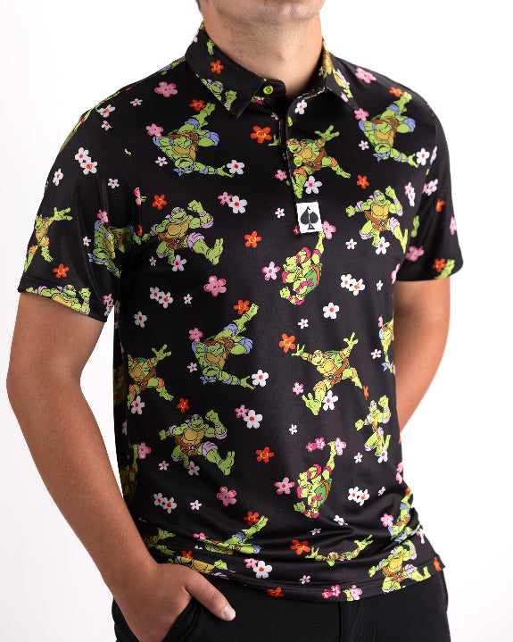 Black TMNT Turtle Flower Power golf polo by Pins & Aces featuring colorful Teenage Mutant Ninja Turtles characters and floral print.