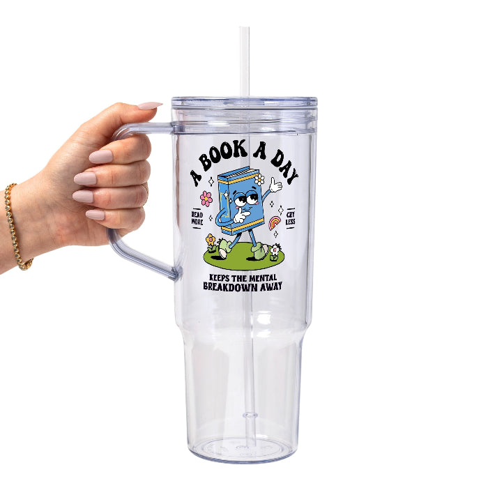 White mug featuring a colorful retro walking book character with flowers and a rainbow, “A Book A Day” lettering, “Read More Cry Less,” and “Keeps the Mental Breakdown Away” text.
